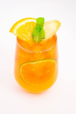 Dilimlenmiş limon ve nane yapraklı ferahlatıcı turuncu narenciye kokteyli beyaz arka planda buzun üzerinde servis edilir. Yüksek kalite fotoğraf