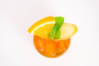 Dilimlenmiş limon ve nane yapraklı ferahlatıcı turuncu narenciye kokteyli beyaz arka planda buzun üzerinde servis edilir. Yüksek kalite fotoğraf