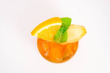 Dilimlenmiş limon ve nane yapraklı ferahlatıcı turuncu narenciye kokteyli beyaz arka planda buzun üzerinde servis edilir. Yüksek kalite fotoğraf