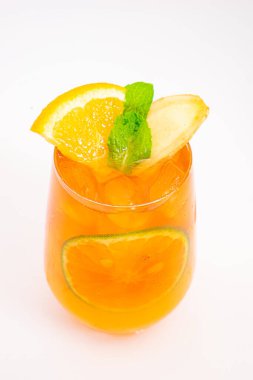 Dilimlenmiş limon ve nane yapraklı ferahlatıcı turuncu narenciye kokteyli beyaz arka planda buzun üzerinde servis edilir. Yüksek kalite fotoğraf