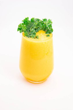 Sarı meyve suyu ya da şeffaf bardakta servis edilen ve temiz beyaz arka planda taze kıvırcık lahana ile süslenmiş meyve suyu. Yüksek kalite fotoğraf