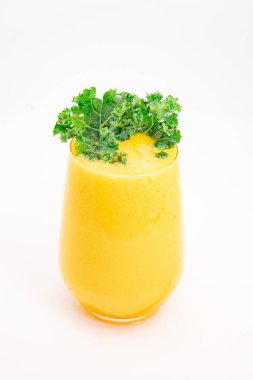 Sarı meyve suyu ya da şeffaf bardakta servis edilen ve temiz beyaz arka planda taze kıvırcık lahana ile süslenmiş meyve suyu. Yüksek kalite fotoğraf