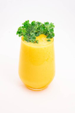 Sarı meyve suyu ya da şeffaf bardakta servis edilen ve temiz beyaz arka planda taze kıvırcık lahana ile süslenmiş meyve suyu. Yüksek kalite fotoğraf