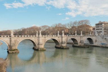Roma 'daki Tiber Nehri üzerindeki Ponte Sant Angelo köprüsünün gündüz manzarası. Yumuşak gökyüzü altındaki su ve klasik mimarinin yansımaları. Yüksek kalite fotoğraf
