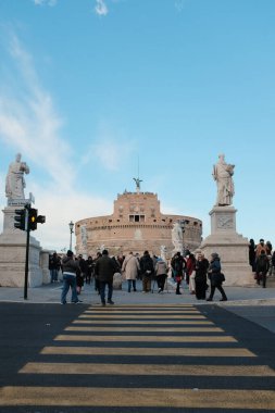Roma 'daki Castel Sant Angelo ve Ponte Sant Angelo' nun gündüz manzarası Tiber Nehri tarihi mimarisi ve açık mavi gökyüzü boyunca yürüyen turistlerle birlikte. Yüksek kalite fotoğraf