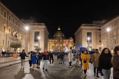 Via della Conciliazione Roma 'dan Aziz Peters Bazilikası' nın gece görüşü. Işıklı sokak lambaları ve simetrik mimari ile yürüyen insanlar. Yüksek kalite fotoğraf