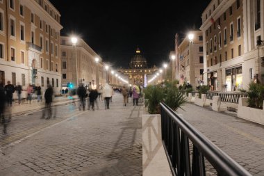Via della Conciliazione Roma 'dan Aziz Peters Bazilikası' nın gece görüşü. Işıklı sokak lambaları ve simetrik mimari ile yürüyen insanlar. Yüksek kalite fotoğraf