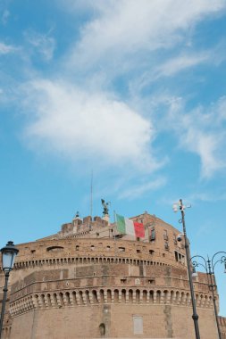 Roma 'da mavi gökyüzünün altında sallanan İtalyan bayraklarıyla Sant Angelo Şatosu dairesel kale ve tarihi simgeleri gösteriyor. Yüksek kalite fotoğraf