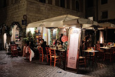 Geceleri dışarıda oturan rahat Roma restoranı. İnsanlar yumuşak ışıklar altında ılık bir ortamda yemek yiyor. Geleneksel İtalyan deneyimi. Yüksek kalite fotoğraf