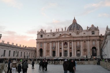 Noel sezonunda gün batımında Aziz Peters Meydanı 'nda Vatikan sütunlarının etrafında süslü ağaç kalabalıkları ve yumuşak pastel gökyüzü vardı. Yüksek kalite fotoğraf