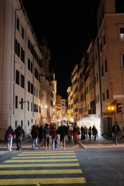 İnsanlar geceleri Roma 'nın göbeğindeki kaldırımlı sokaklarda sokak lambalarının altında Castel Sant Angelo' nun arka planında ve hareketli bir atmosferde yürüyor. Yüksek kalite fotoğraf