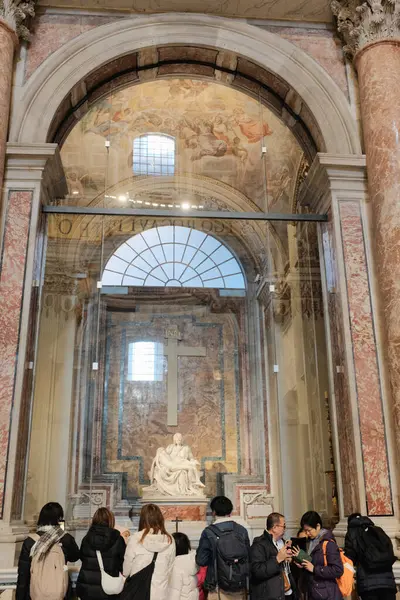 Aziz Peters Bazilika Vatikan Şehri 'nde cam arkasındaki Michelangelos Pieta heykeline hayran olan turistler mermer duvar arkası büyük çapraz freskli tavan ve kemerli pencereden gelen doğal ışık.