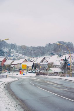 Büyülü kış mevsiminde büyüleyici küçük bir köyde zarif bir şekilde dönen karlı bir yol.