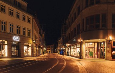 Avrupa 'nın sakin caddesinin gece görüşü. Kış boyunca sıcak ışıklar ve dükkan vitrinleriyle aydınlatılmış tramvay rayları. Yüksek kalite fotoğraf