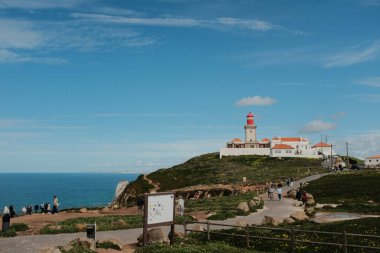 Bereketli yeşil tepeler ve engebeli arazi mavi gökyüzü ve dağılmış bulutlar Cabo da Roca Sintra Portekiz doğal manzarası manzaralı yürüyüş patikasından bitki örtüsü
