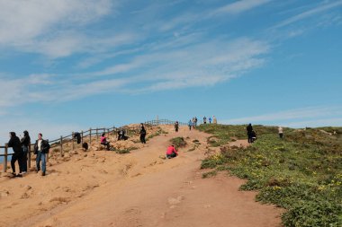 Bereketli yeşil tepeler ve engebeli arazi mavi gökyüzü ve dağılmış bulutlar Cabo da Roca Sintra Portekiz doğal manzarası manzaralı yürüyüş patikasından bitki örtüsü