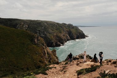 Bereketli yeşil tepeler ve engebeli arazi mavi gökyüzü ve dağılmış bulutlar Cabo da Roca Sintra Portekiz doğal manzarası manzaralı yürüyüş patikasından bitki örtüsü