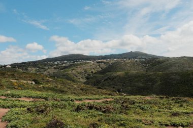 Bereketli yeşil tepeler ve engebeli arazi mavi gökyüzü ve Cabo da Roca Sintra Portekiz 'de dağılmış bulutlar manzaralı yürüyüş patikasından gelen bitki örtüsü ile doğal manzara. Yüksek kalite fotoğraf