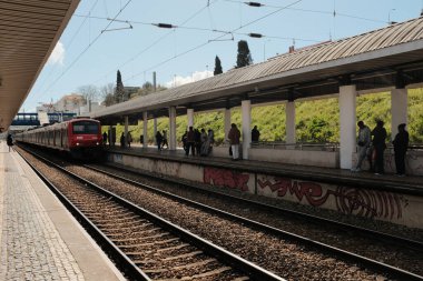 Güneşli bir günde Lizbon 'daki banliyö platformunda kırmızı banliyö treninde bekleyen yolcular ve kentsel Avrupa' daki toplu taşıma sahnesinde her gün duvarlara graffiti çizen yolcular. Yüksek kalite fotoğraf