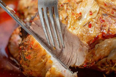 Kızarmış domuz eti, çıtır çıtır ve baharatlı bir kabukla yakın plan çekimde çatal ve bıçakla sulu dokusunu gözler önüne seriliyor. Restoran menüsü.