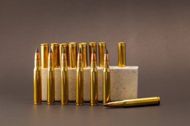 Hunting ammunition: 30-06 cartridges with polished brass casings and black ballistic tips on a dark background. clipart