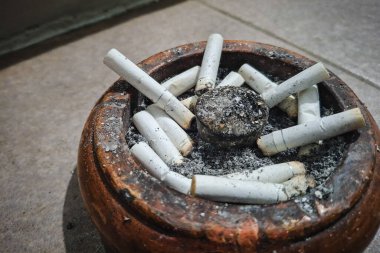 Ahşap bir kül tablasında pek çok beyaz sigara izmaritinin yakın plan görüntüsü.