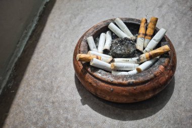 Tahta kül tablasında bir sürü sigaranın portresi