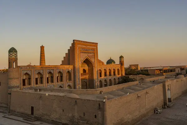 Muhammed Rahim Khan Madrasah 'ın göz kamaştırıcı yüzü yaz güneşinin altında ışıl ışıl parlıyor. Khiva' nın eski kasabasında kartonpiyer ve tarihi bir cazibe sergiliyor.