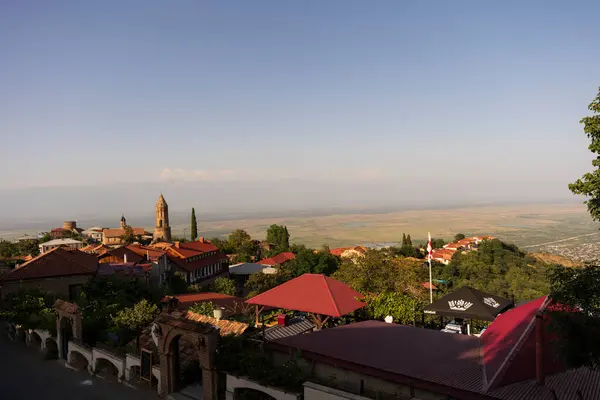 Gürcistan 'ın Sighnaghi kentinin panoramik bir görüntüsü, güneşli bir gökyüzünün altında geniş, düz bir zemin üzerinde büyüleyici kırmızı çatılı evleri sergiliyor..