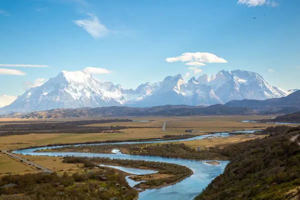 Uzakta görkemli Torres del Paine dağlarıyla vadide sürünen Iago Grey 'in nefes kesici manzarası. Açık gün Patagonya 'nın doğal güzelliğini vurguluyor.