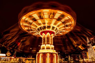 Spinning carousel with Christmas decor at Tivoli Gardens, Copenhagen. Blurred figures enhance the lively holiday atmosphere. clipart