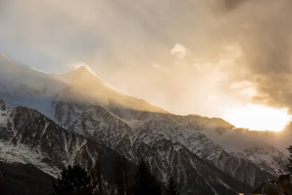 Güneş bulutları delip geçer ve sabah Chamonix dağlarında parlar. Açık bir kış gününde bulutlar dağılıyor.