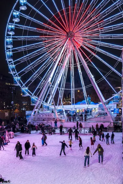 İnsanlar Oslo Noel Pazarı 'nda buz pateni yaparken, arka planda yanan dönme dolap gece boyunca parlıyordu.