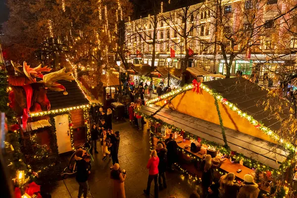 Oslo 'daki hareketli Noel pazarının gece manzarası. Kalabalık, şehir merkezinde festival ışıklarının ve mevsimlik atmosferin keyfini çıkarıyor..