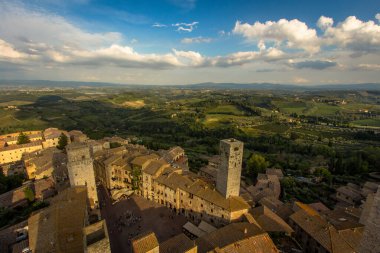 San Gimignano 'dan Torre Grossa' nın Piazza del Duomo manzarası ve tarihi eski şehrin ötesindeki geniş manzara..