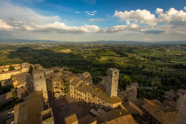 San Gimignano 'dan Torre Grossa' nın Piazza del Duomo manzarası ve tarihi eski şehrin ötesindeki geniş manzara..
