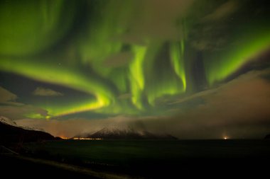 Mother and baby admire the northern lights on a clear winter night in Tromso, Norway, with aurora visible in the sky. clipart