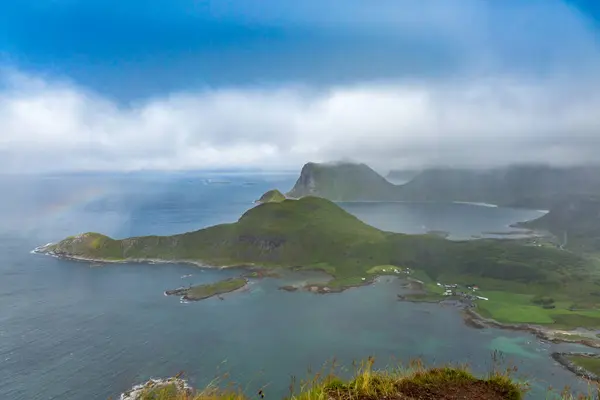 Norveç, Lofoten 'de alçak bulutların üzerindeki bir yürüyüşten muhteşem bir manzara. Mavi gökyüzü ve görkemli tepeler büyülü bir atmosfer yaratır..