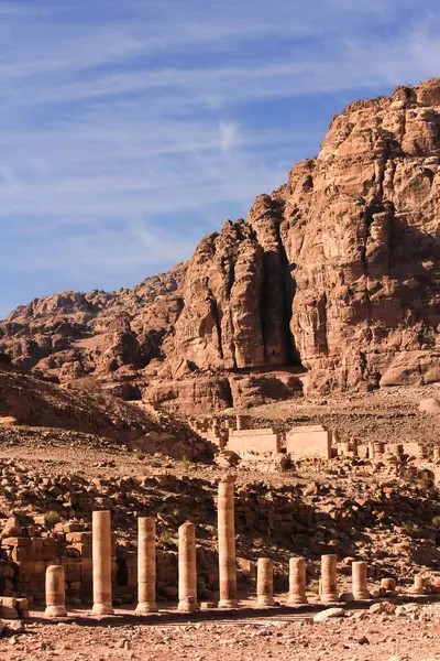 Petra, Ürdün 'deki Roma harabeleri, açık bir günde güneşin altında engebeli kayalık manzaraların önünde duruyor..