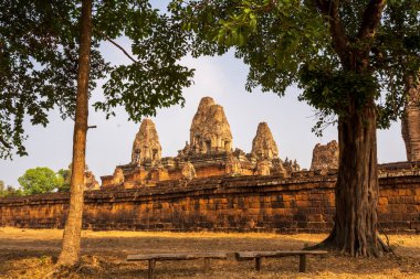 Pre Rup tapınağı berrak güneşli bir gökyüzünün altındaki gür ağaçlar arasında güzel bir şekilde belirir. Eski ihtişamını ve dinginliğini ön plana çıkarır..