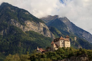 Lihtenştayn 'daki bir şatonun manzarası, kısmen güneşli bir günde arka planda dağlar olan bir tepeye tünemişti. Tarih ve doğanın resimli bir sahnesi..