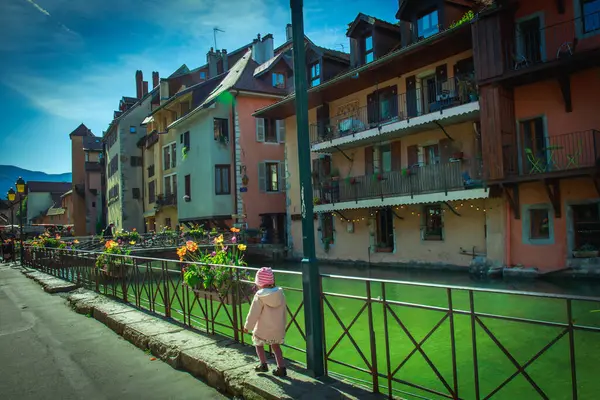 Güneşli bir bahar günü, Annecy 'nin eski kasabasındaki yeşil nehrin kıyısında küçük bir kız yürür. Nehir kıyısında tarihi evler ve balkonlar yer alıyor..