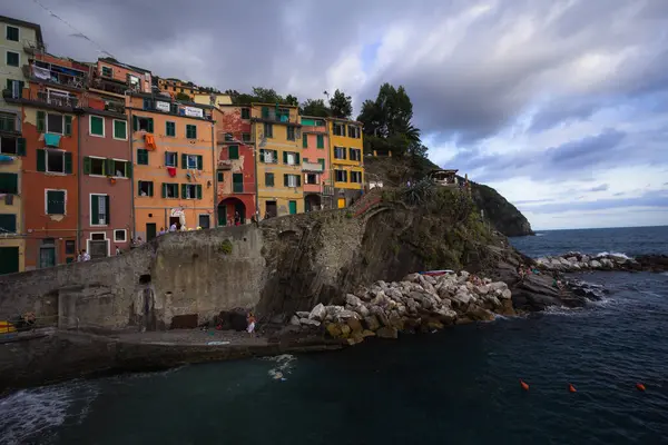 Manarola manzarası, İtalya Cinque Terre 'nin bir parçası. İnsanlar okyanusta yıkanırken kayalıkların tepesindeki renkli evler göz kamaştırıcı bir manzara yaratıyor..