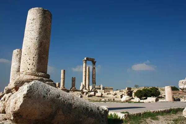 Yıpranmış Roma sütunları, geçmişten gelen yankıları koruyan, Roma 'nın Amman Forumunda parlak Ürdün güneşine karşı dururlar.