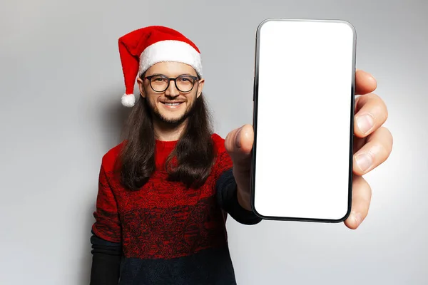배경에 빨간색 모자의 크리스마스 스웨터를 스마트폰을 머리를 청년의 스튜디오 Mockup — 스톡 사진