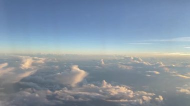 Bulutların üstündeki gökyüzünü güzel günbatımında uçağın penceresinden görmek.