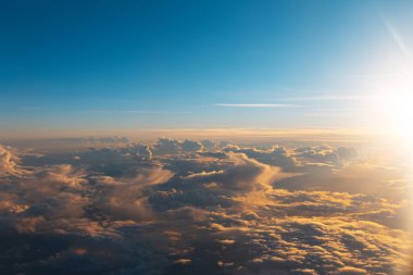 Gökyüzünün doğal arka planı, kara bulutların üzerinde gün doğumu, uçuş sırasında uçağın içinden pencereyi görmek..