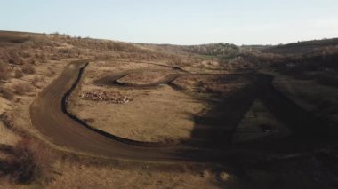 Aerial view of rally roads in dry field between hills. Winter time. Filming by drone. Moldova land. Sheeps in the meadow.