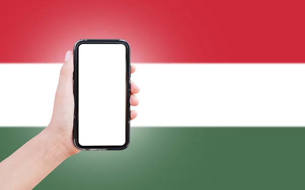 Mies Käsi Tilalla Älypuhelin Tyhjä Ruudulla Taustalla Hämärtynyt Unkarin Lippu — kuvapankkivalokuva