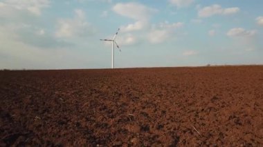 Tarımsal alandaki rüzgar türbininin havadan görünüşü. İnsansız hava aracından video çekmek. Çevresel konsept. Yel değirmeni yeşil enerji üretiyor. Bereketli topraklar.